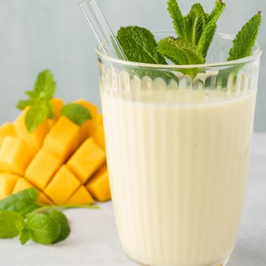Ananas Smoothie mit Mango in einem Trinkglas mit Strohhalb und frischer Minze