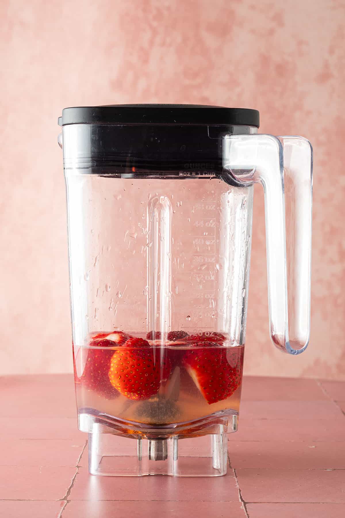 Mixerbehälter Erdbeeren, Wasser und Agavendicksaft.