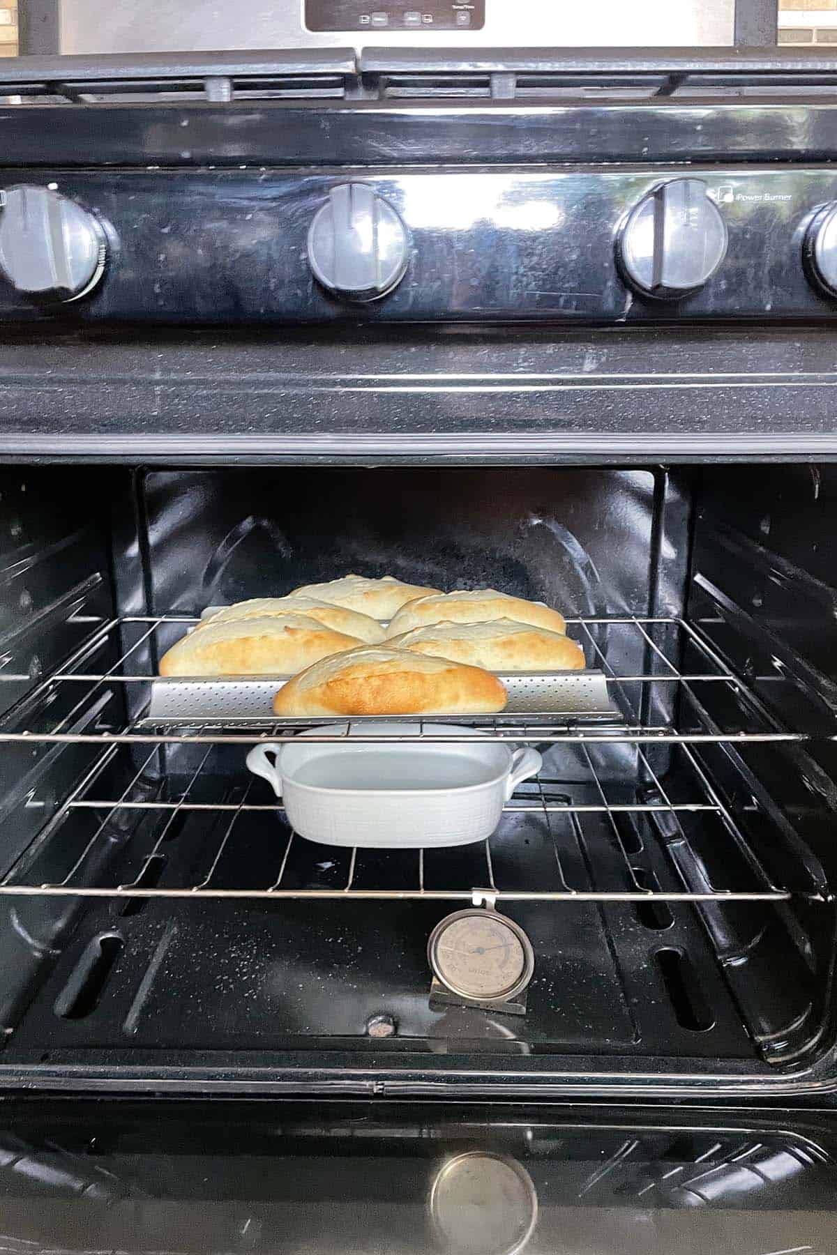 Baguette-Brötchen backen im Ofen, mit einer Schale Wasser und Ofenthermometer auf dem Rost.