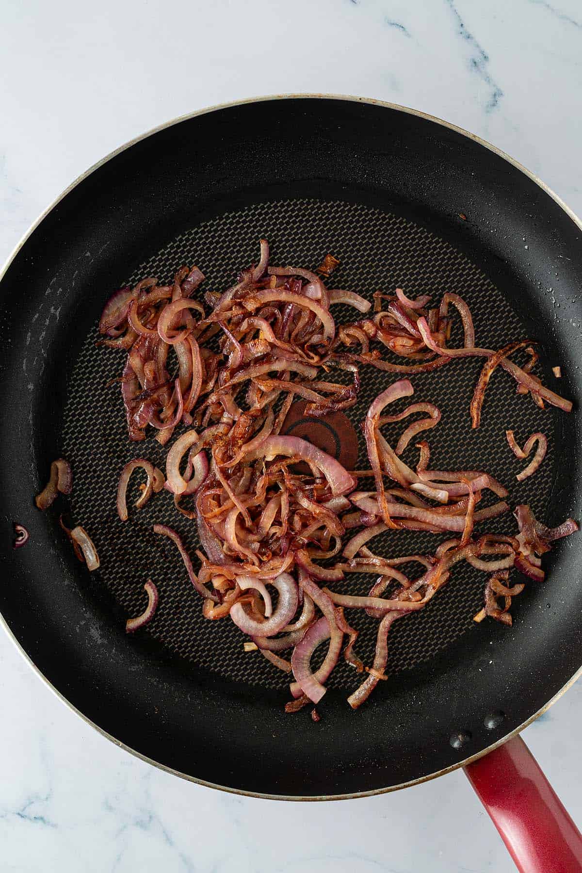Knusprig gebratene rote Zwiebeln in einer Pfanne.