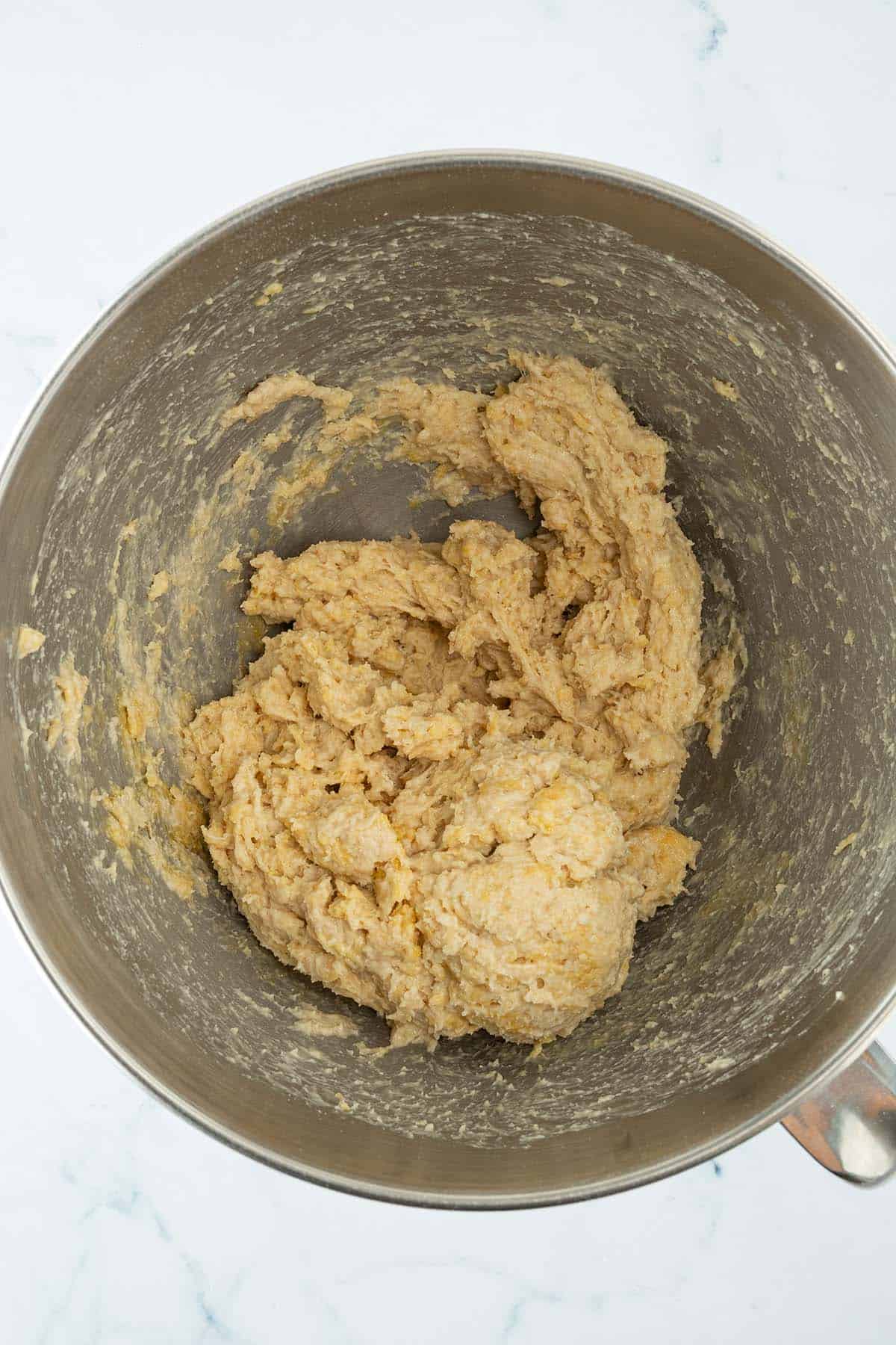 Brioche-Teig w&auml;hrend des Knetens in der R&uuml;hrsch&uuml;ssel, bevor sich ein glatter und elastischer Teig entwickelt hat.