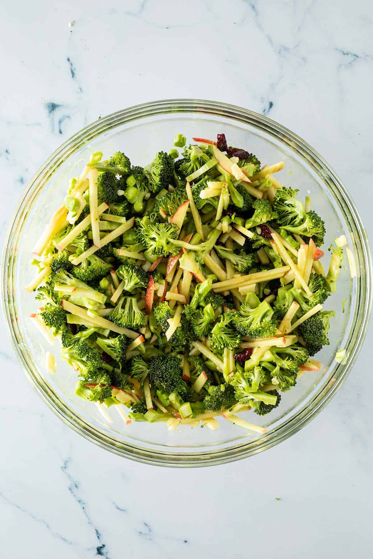 Fein geschnittener Brokkoli in einer gro&szlig;en Sch&uuml;ssel vermengt mit Apfelstiftchen, Cranberries, K&auml;se und Dressing.