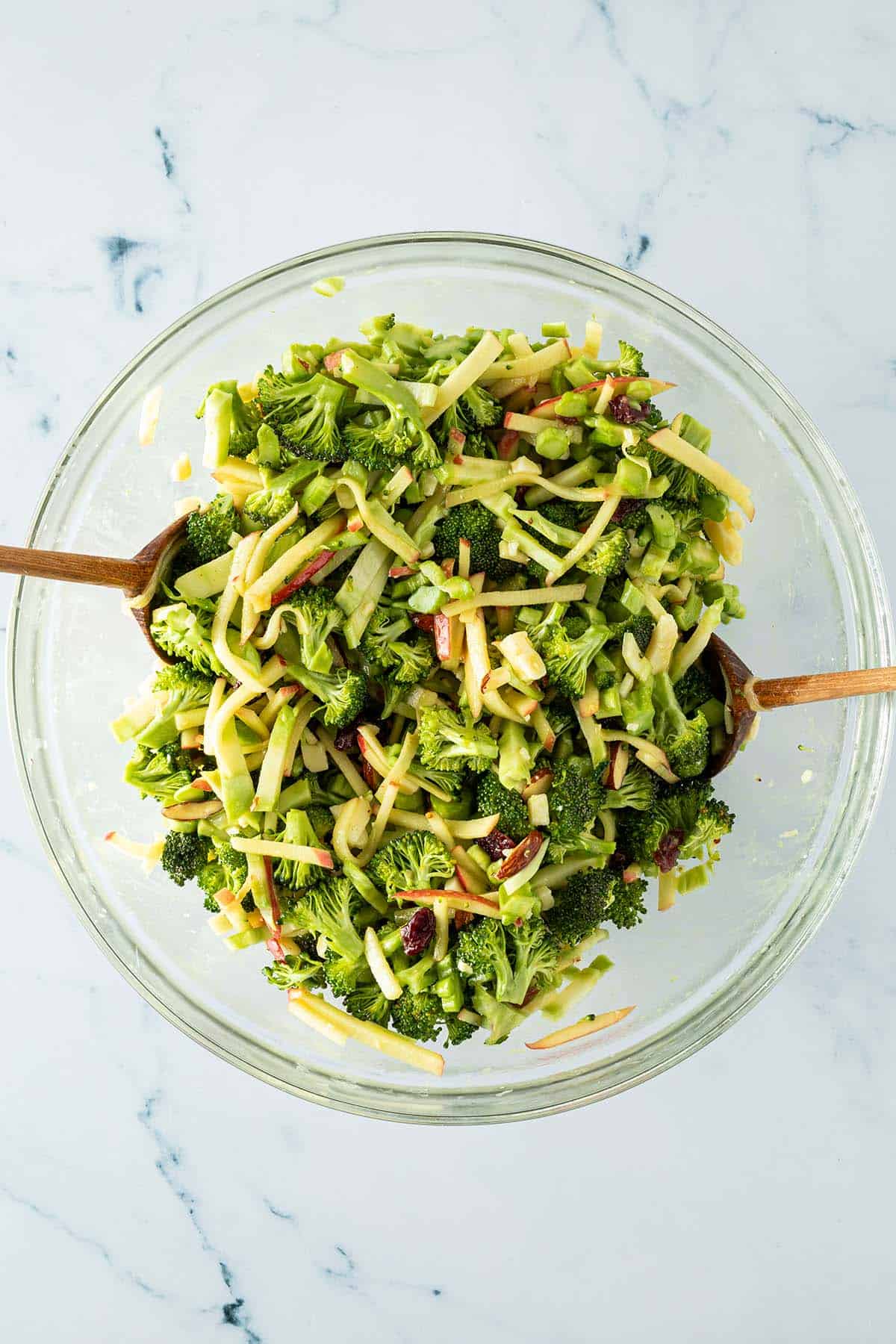 Fertiger Brokkolisalat wird vor dem Servieren in einer Sch&uuml;ssel mit grob gehackten Mandeln vermischt.