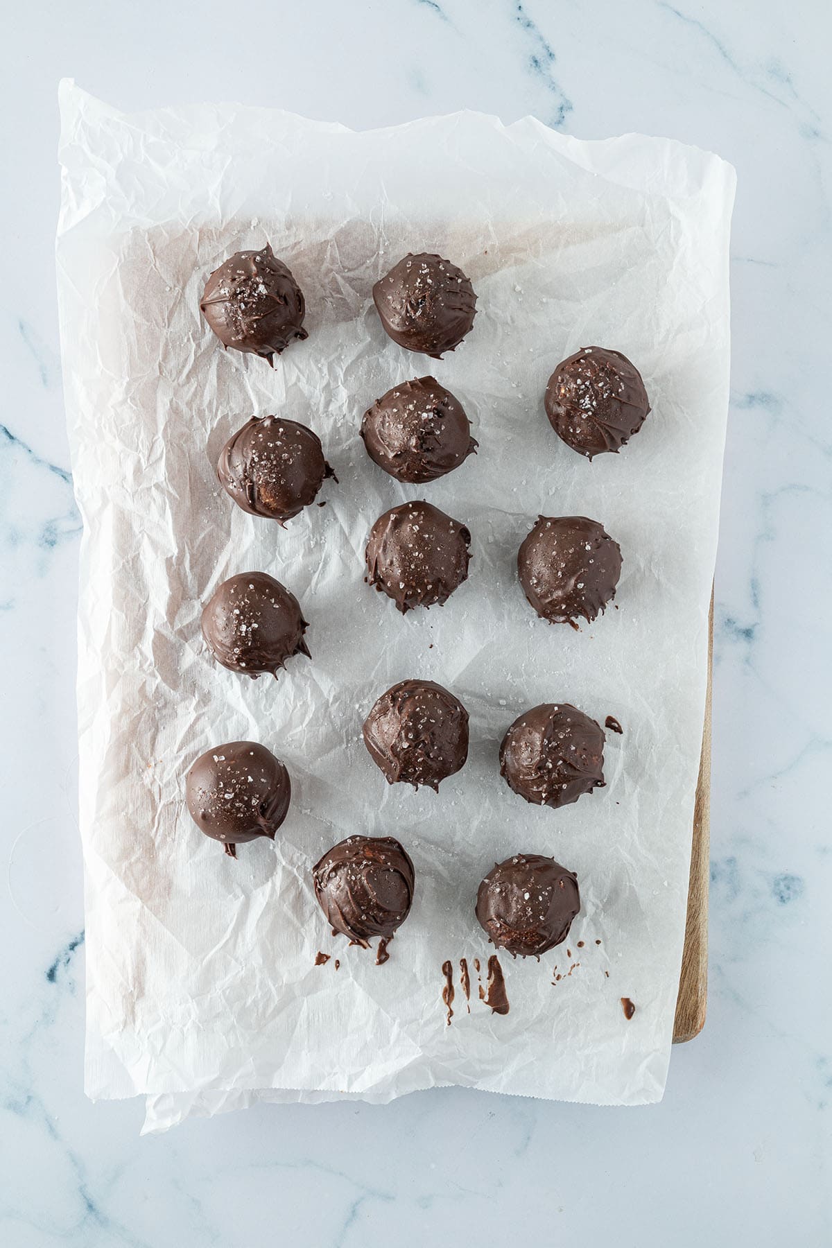 Mit Schokolade überzogene Energy Balls auf einem Stück Backpapier.