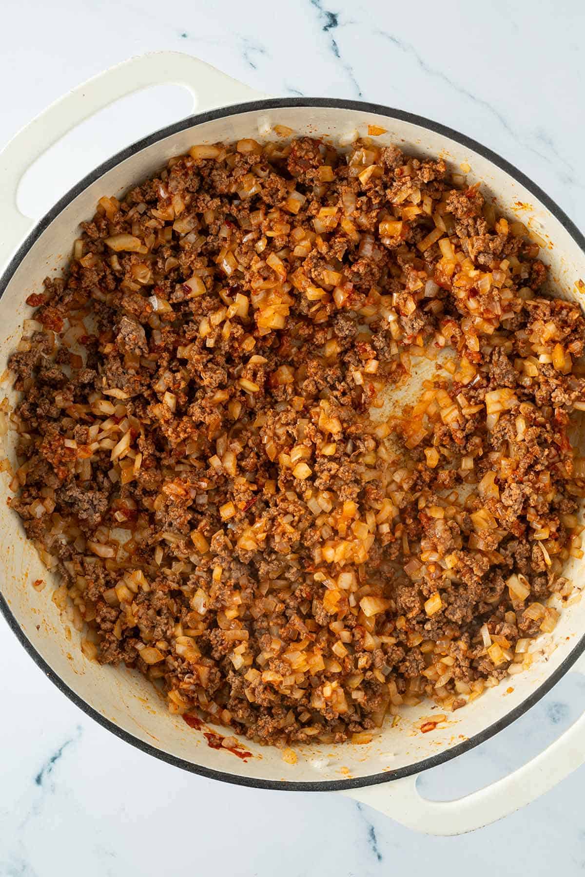 Eine große Pfanne mit angebratenem Hackfleisch und Zwiebeln.