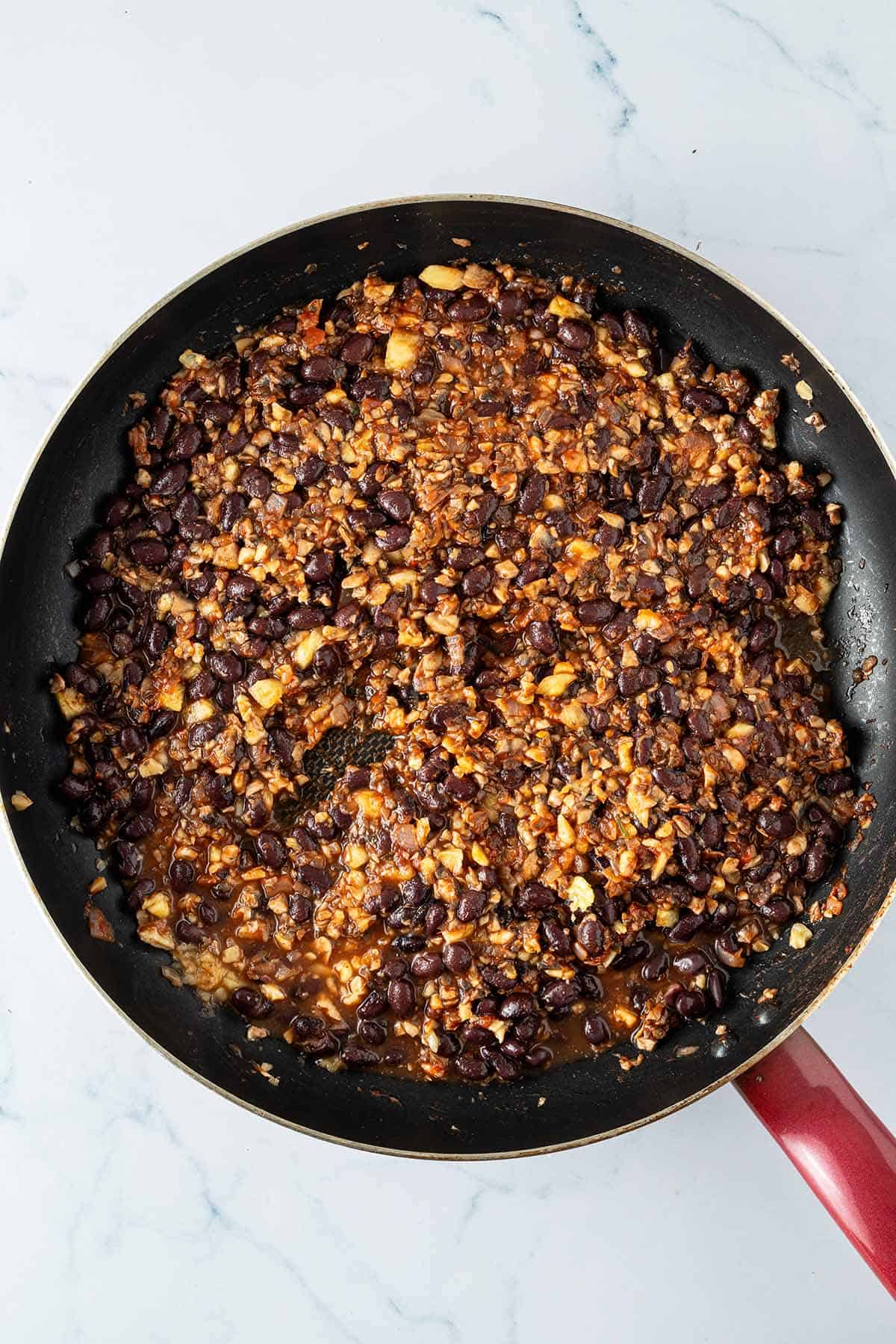 Schwarze Bohnen und fein gehackte Champignons, Walnüssen, Ananas und Salsa köcheln für die Taco-Füllung in einer Pfanne.