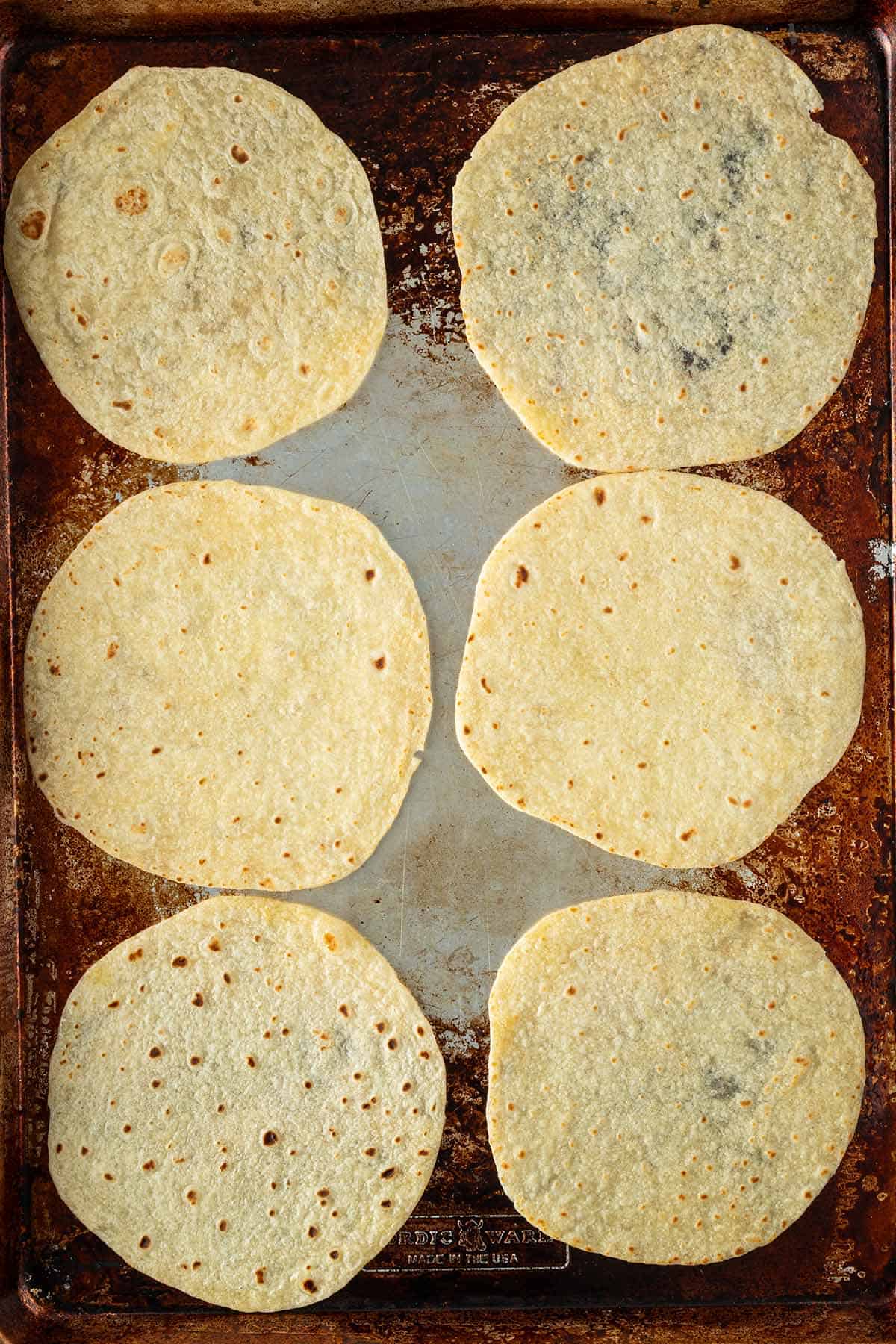 Tortillas auf einem Backblech als Vorbereitung für knusprige Crispy Tacos.