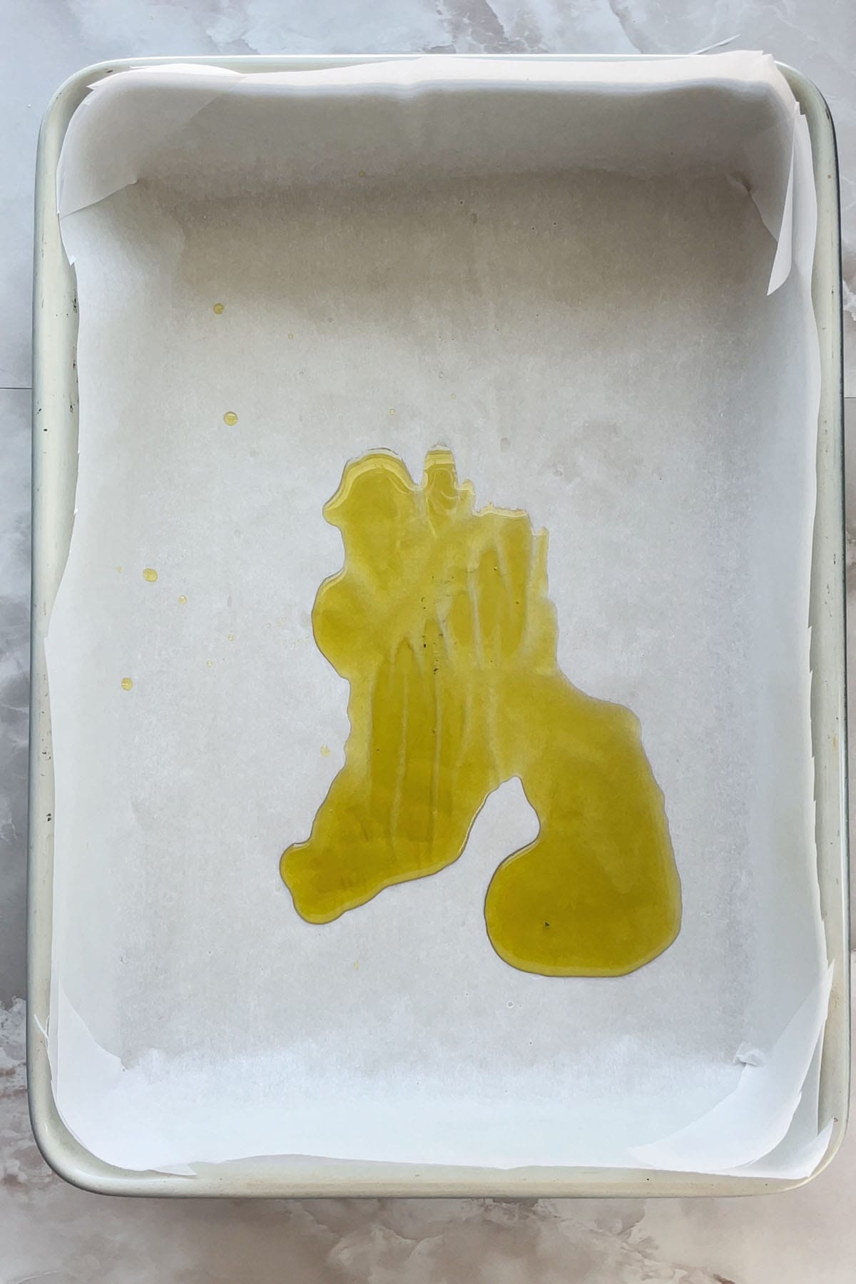 Olivenöl in einer mit Backpapier ausgelegten Backform.