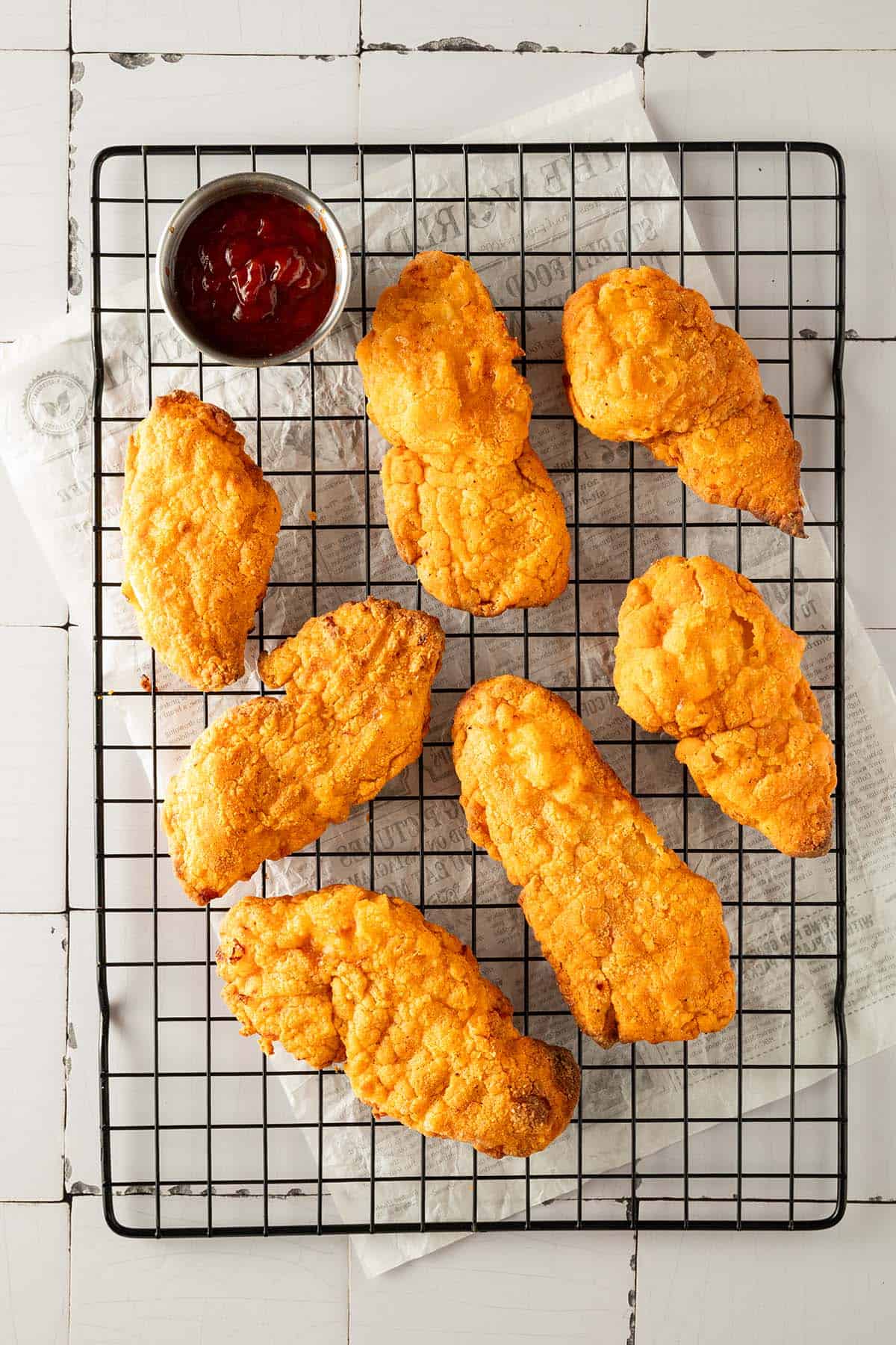 Knuspriges Fried Chicken aus dem Airfryer mit Ketchup auf einem Gitter.