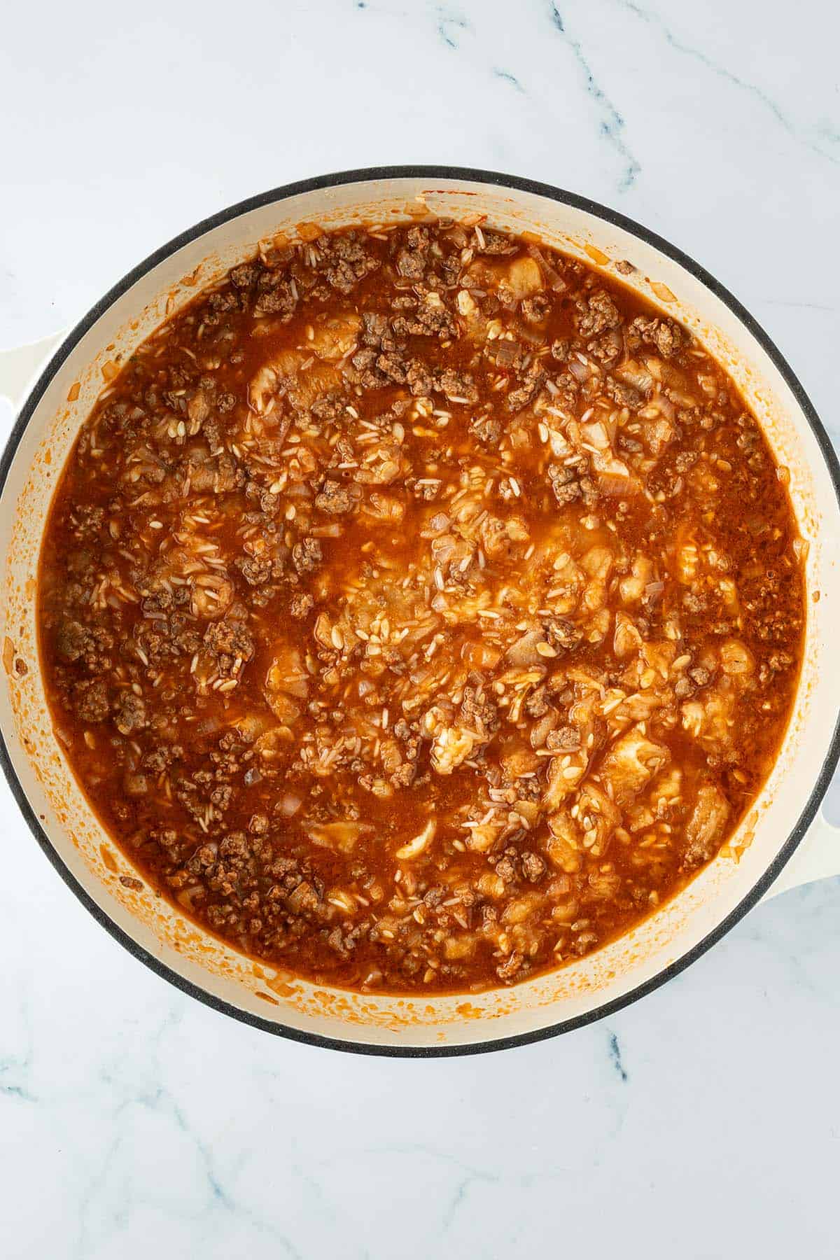 Hackfleisch, ungekochter Reis und Zucchinifruchtfleisch in einer Tomatensauce vorm Kochen.