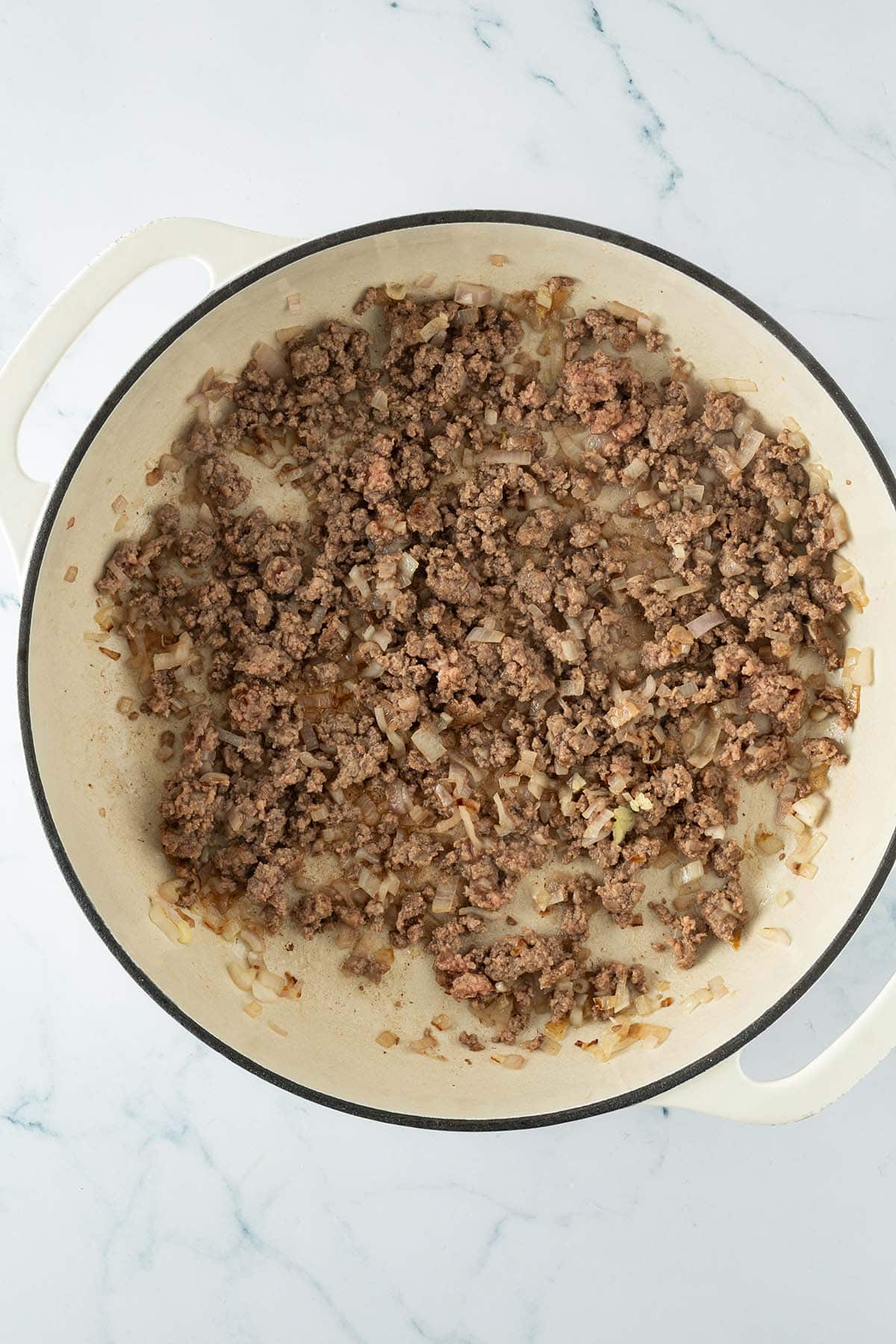 Gebratenes Hackfleisch mit Zwiebeln in einer Pfanne, leicht gebräunt.