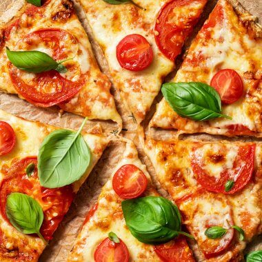 Vollkorn Pizza belegt mit Käse, Tomaten und Basilikum.