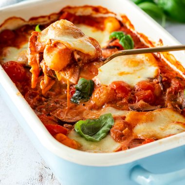 Vegetarischer Gnocchi Auflauf mit Tomate Mozzarella und frischem Basilikum in einer Auflaufform.