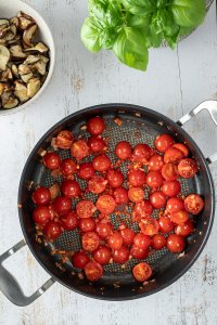 Cherry Tomaten, Zwiebel und Knoblauchwürfel in einer großen Pfanne.