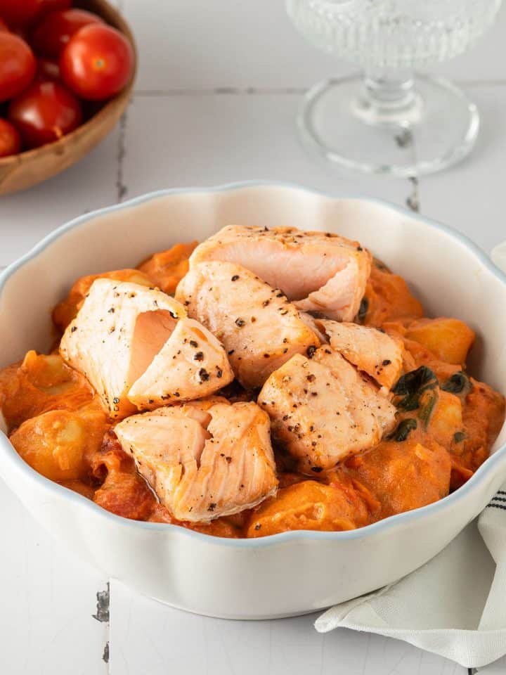 Cremige Gnocchi mit Lachs in tomatiger Marry Me Sahnesauce, angerichtet in einer weißen Schüssel auf hellem Untergrund.