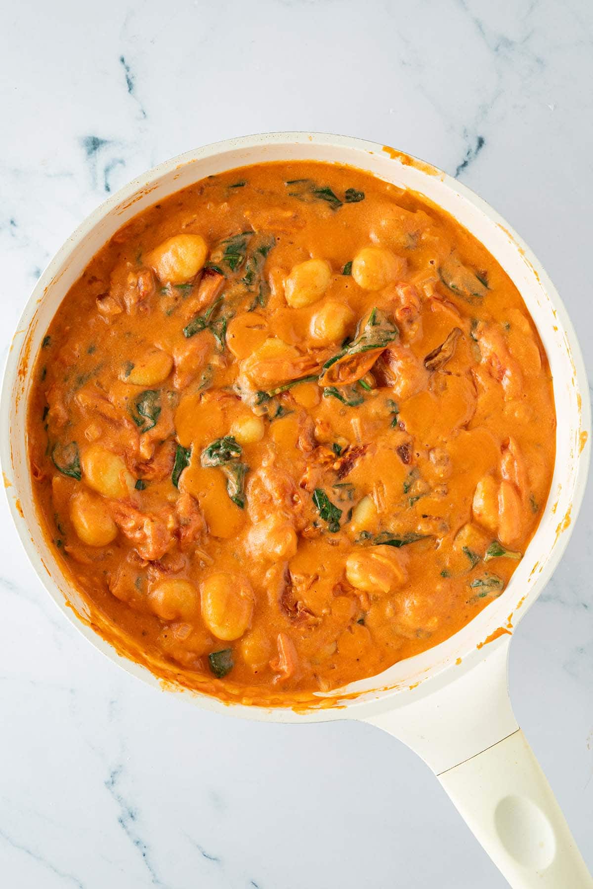 Cremige Tomaten-Sahne-Sauce mit Gnocchi, getrockneten Tomaten und Spinat in einer Pfanne.