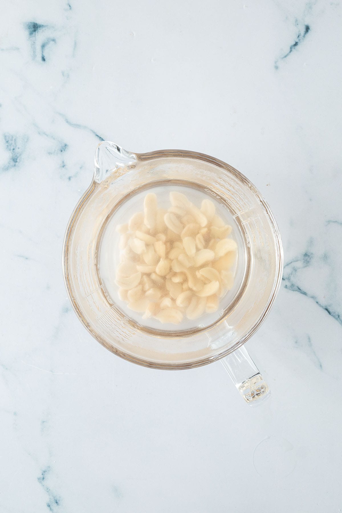 Cashewkerne eingeweicht in einem Messbecher mit Wasser.