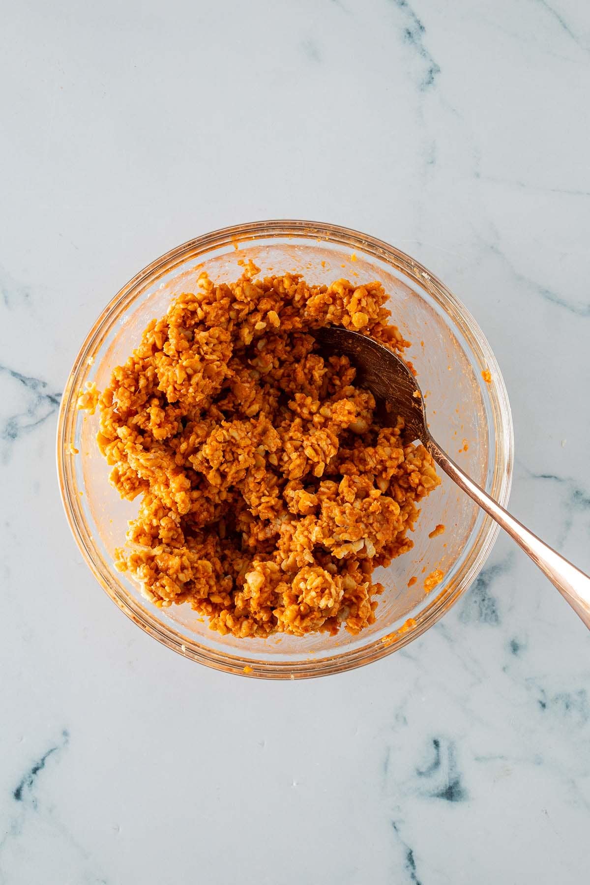 Auf einer Kastenreibe geraspelter Tempeh in einer Sch&uuml;ssel, wo er mit einer Gochujang Marinade verr&uuml;hrt wird.
