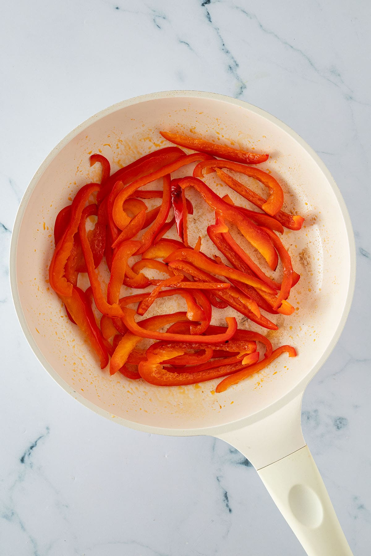 Paprikastreifen werden in einer Pfanne angebraten.