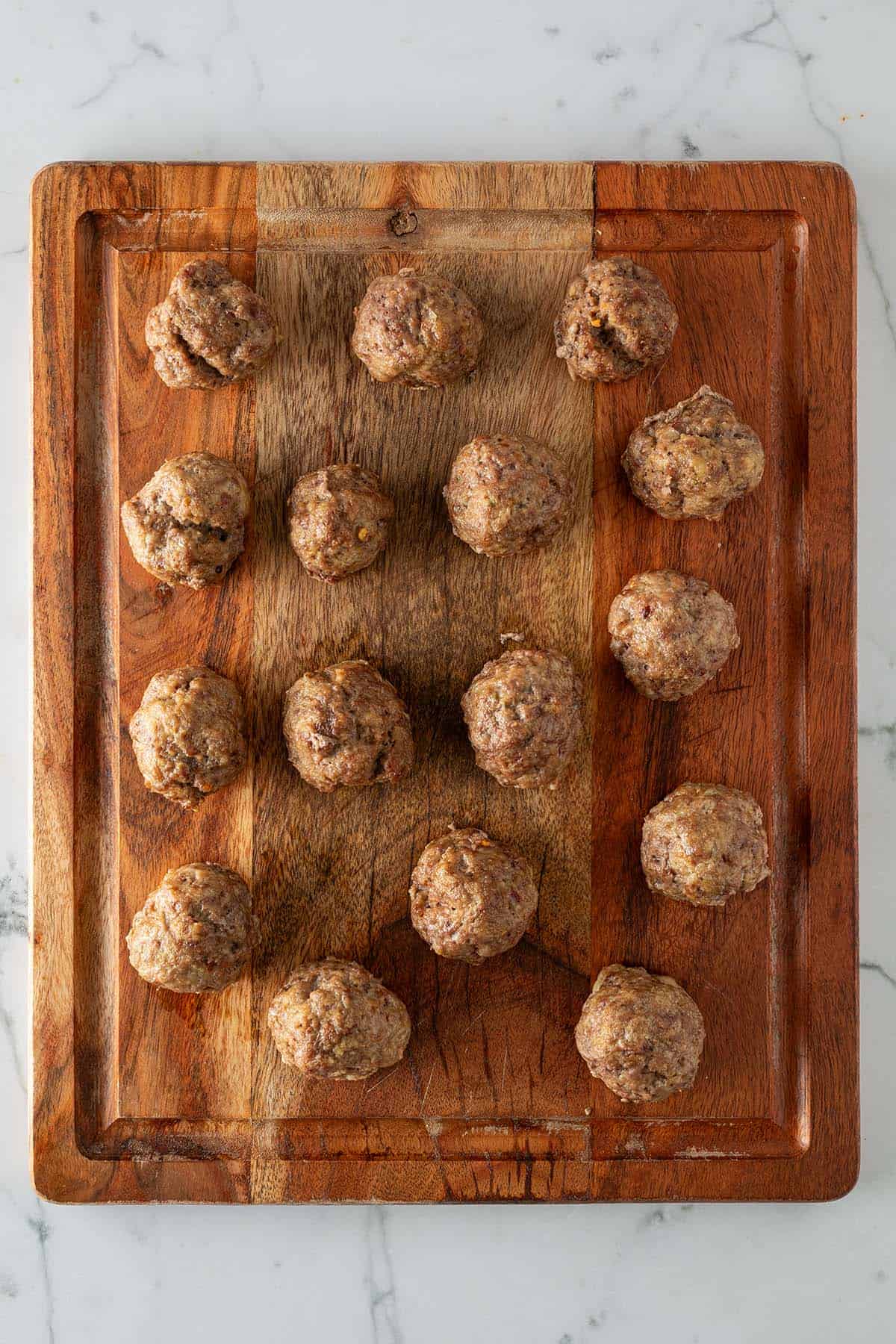 Im Ofen gebackene Hackb&auml;llchen auf einem Holzbrett.