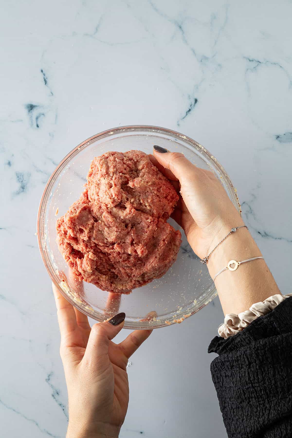 Eine Hand hebt das Hackfleisch unter die Semmelbr&ouml;selmischung.