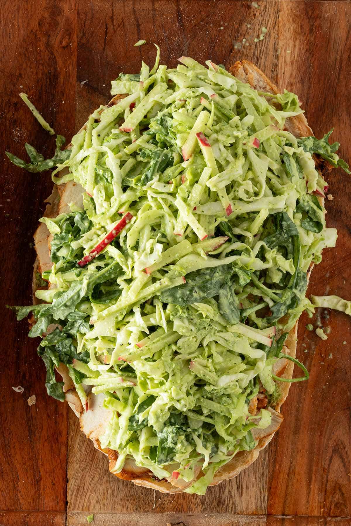 Offenes Sandwich mit H&auml;hnchen, Aji Verde und Wei&szlig;kohlsalat von oben fotografiert auf einem Holzbrett.