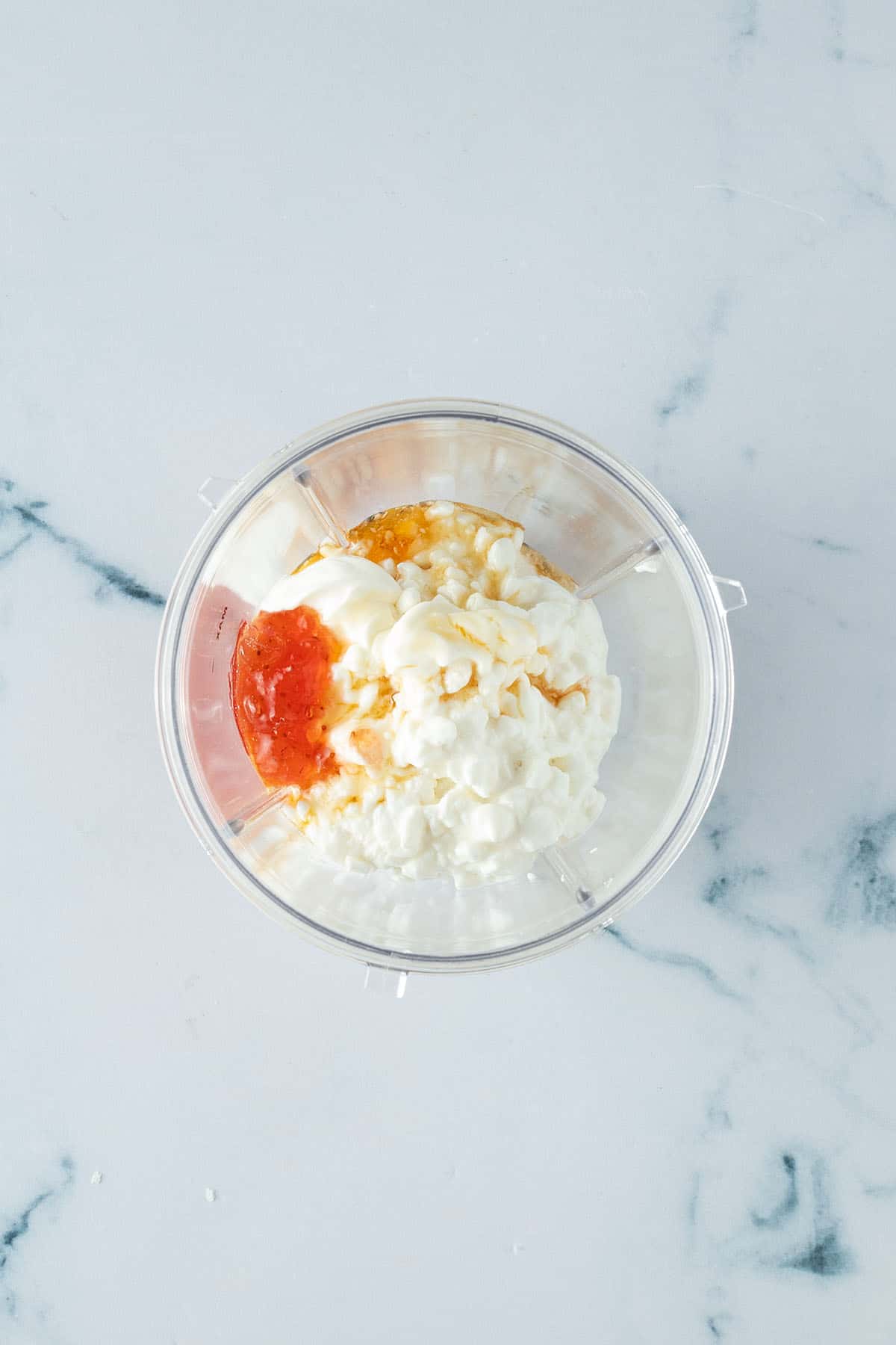 Hüttenkäse, Schmand, Marmelade und Honig in einem Becher.