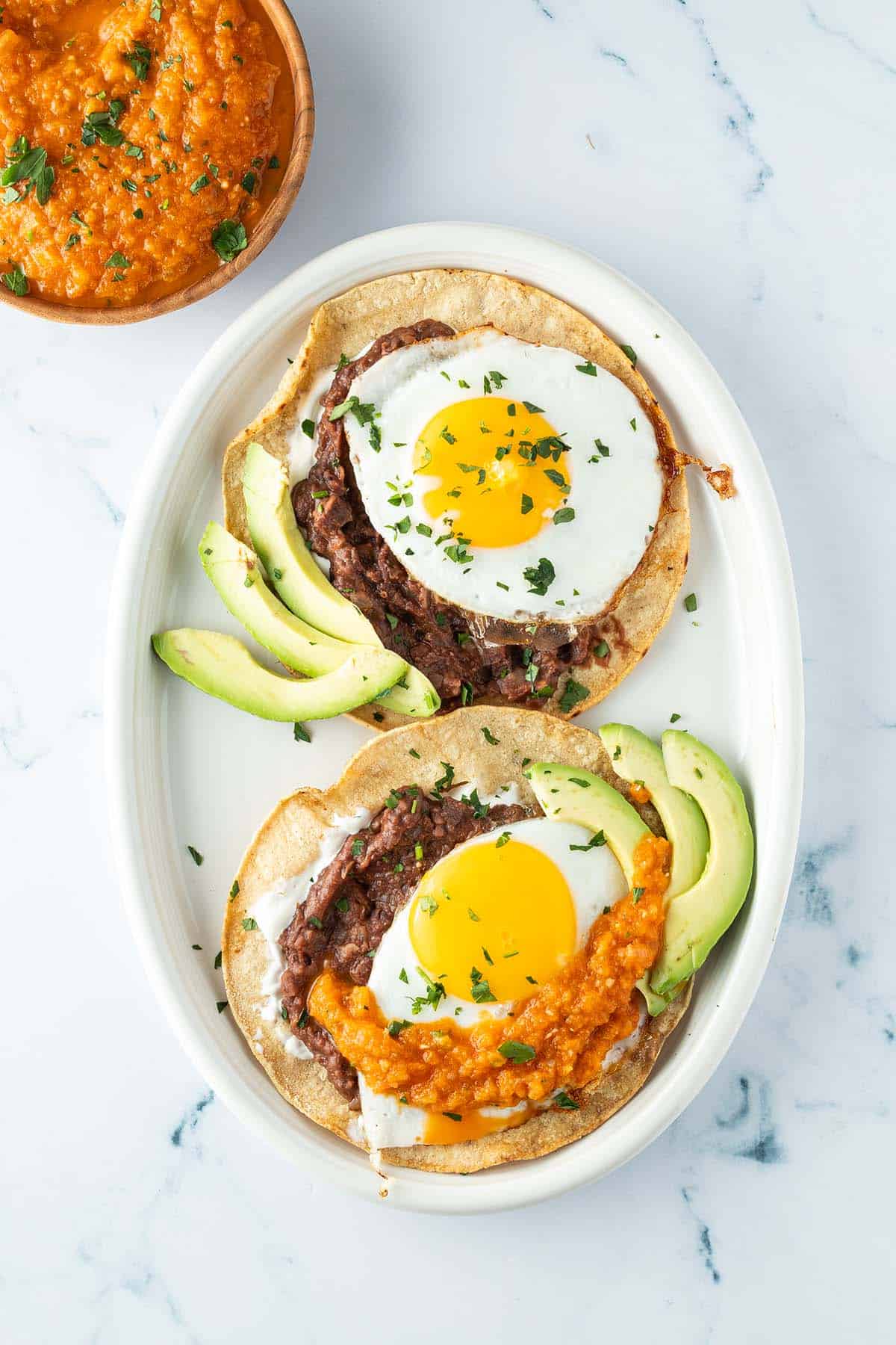 Fertig belegte Huevos Rancheros mit Avocadospalten und Salsa.