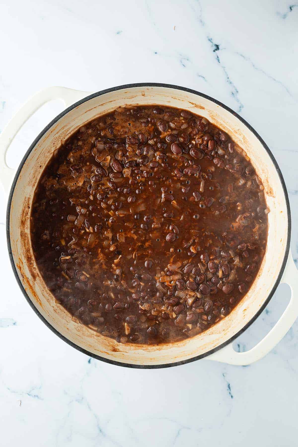 Schwarze Bohnen kochen in einer Pfanne.