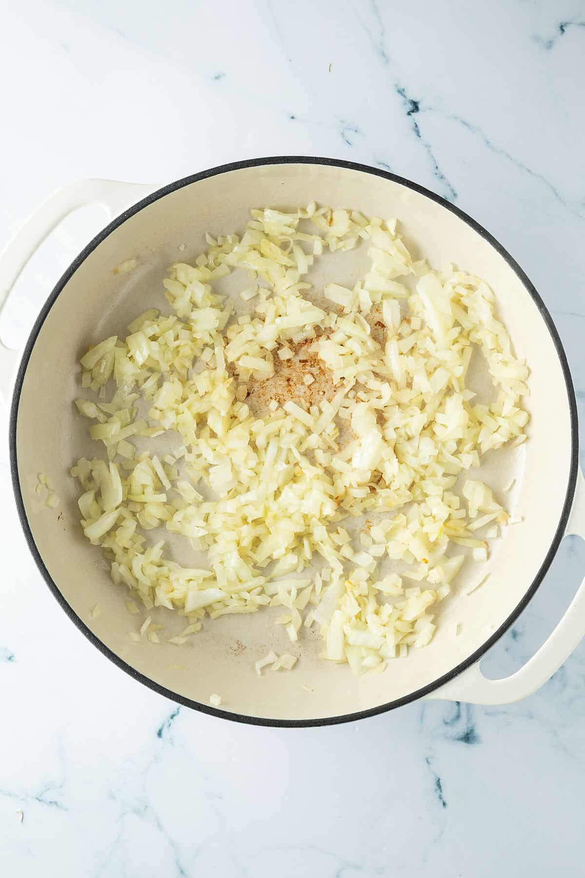Glasig angebratene Zwiebeln in einer großen Pfanne.