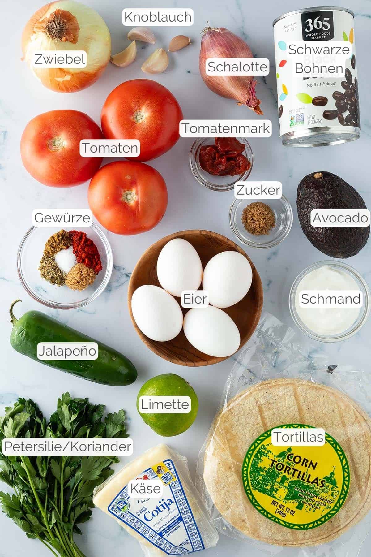 Alle Zutaten mit Textbeschriftungen, die für hausgemachte Huevos Rancheros benötigt werden.