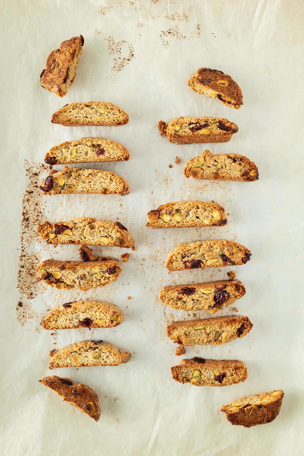 Frisch gebackene Biscotti mit Cranberries und Pistazien in Reihen auf einem Backpapier ausgelegt.