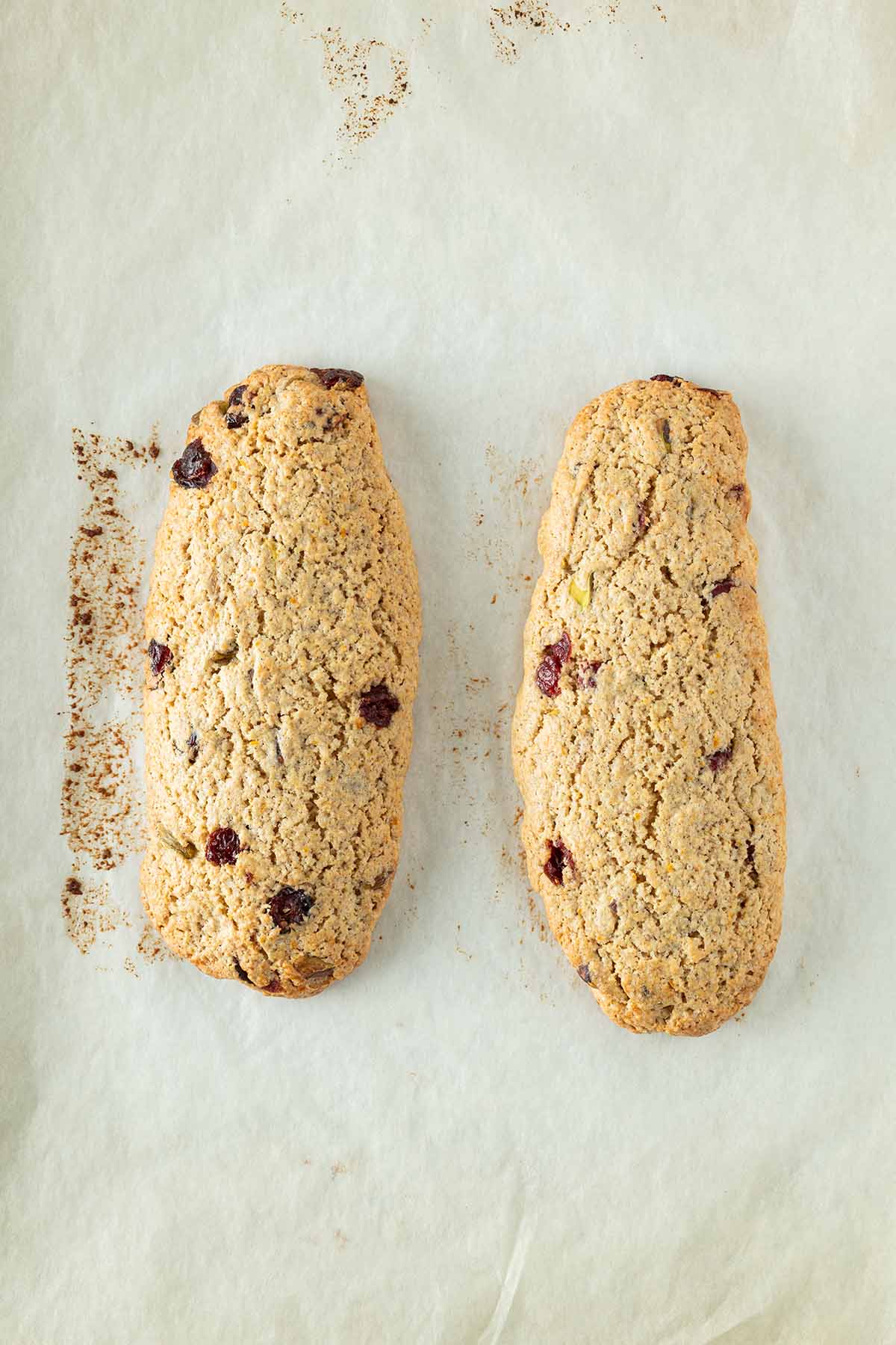 Zwei goldbraune Biscotti-Teigstränge nach dem ersten Backen auf Backpapier.