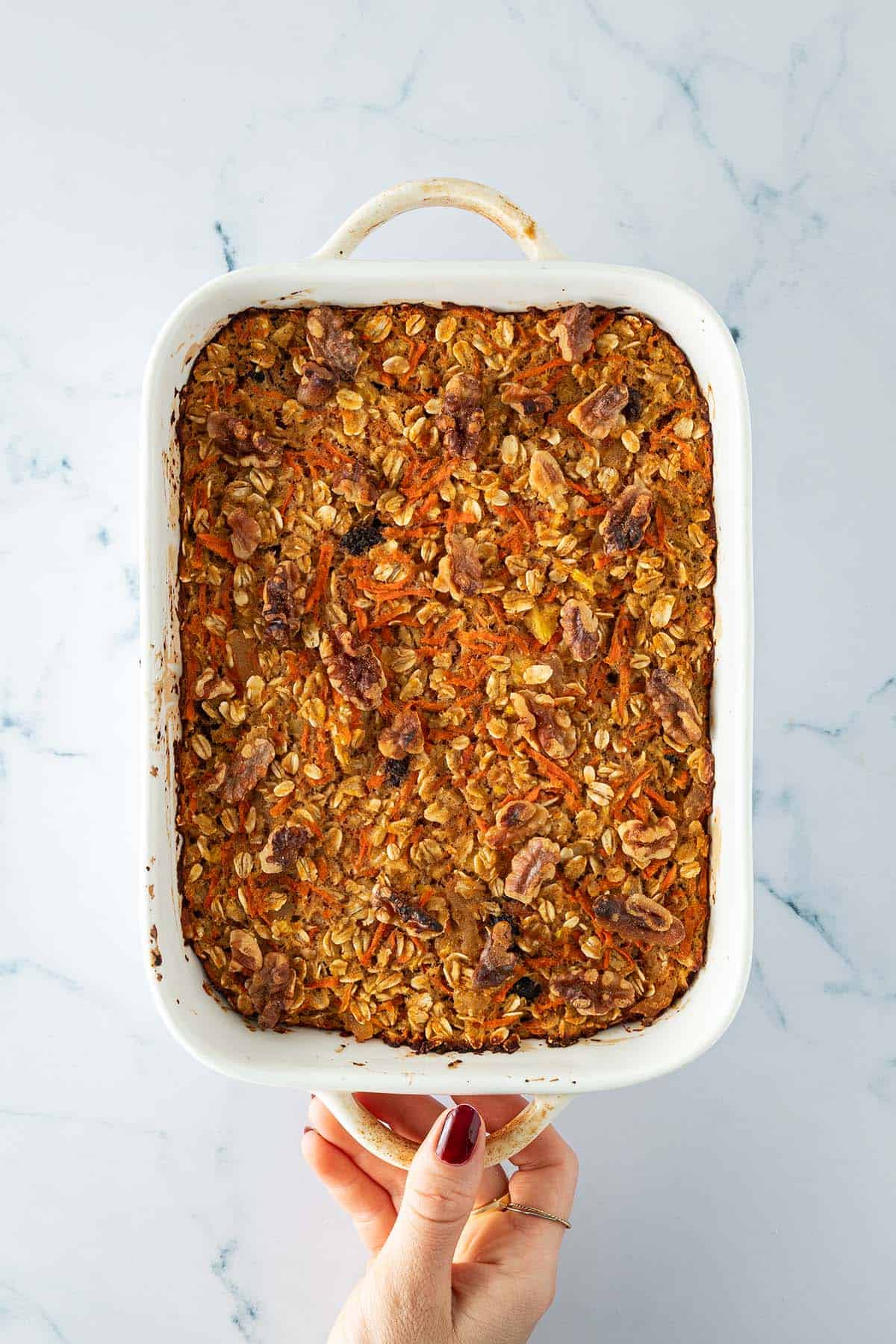 Frisch gebackene Karotten-Baked-Oats in weißer Auflaufform, von oben fotografiert.