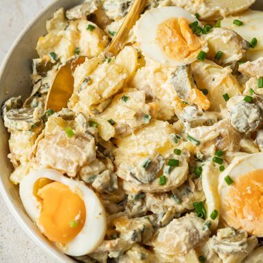 Schüssel mit cremigen Kartoffelsalat angemacht mit Joghurtdressing, Eiern und frischen Schnittlauch.