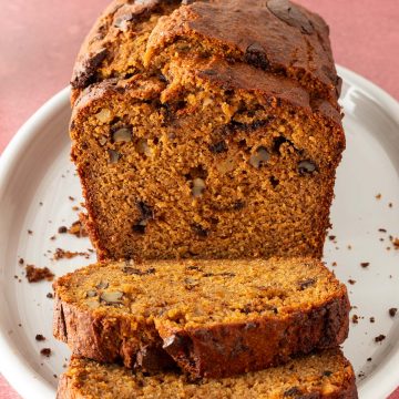 Kürbis-Bananenbrot aufgeschnitten auf einem ovalen roten Teller auf einem roten Untergrund.