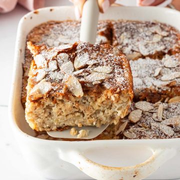 Eine Portion Mandel-Croissant Baked Oats wird mit einem Spatel aus einer Auflaufform gehoben.