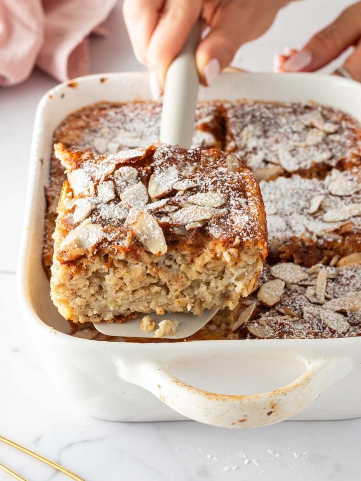 Eine Portion Mandel-Croissant Baked Oats wird mit einem Spatel aus einer Auflaufform gehoben.