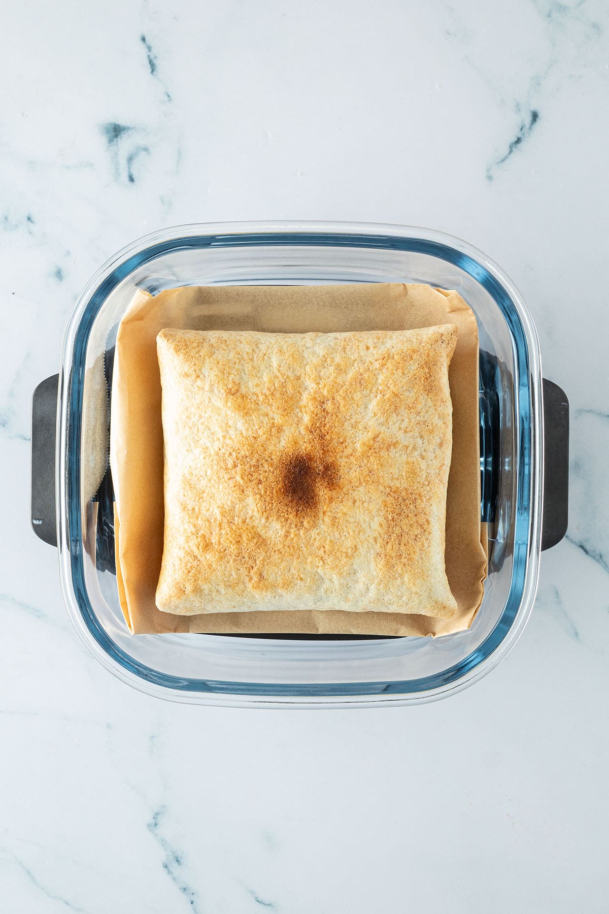 Goldbraun getoastetes Frühstückssandwich in einer Glas-Airfryer mit Backpapier.