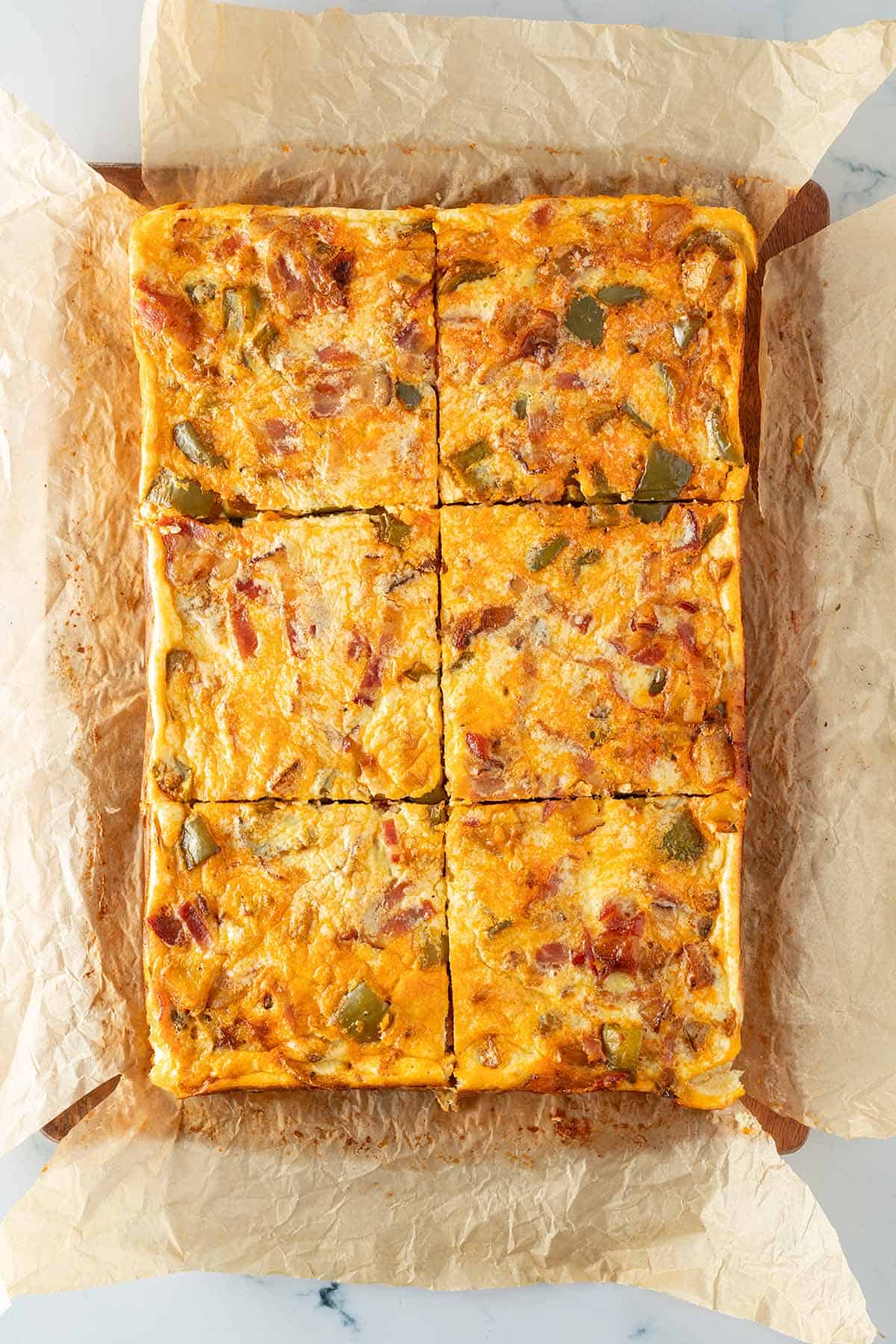 Großes, Gebackene Ofen-Omelett mit Paprika, Kartoffeln und Speck in sechs gleichmäßige Quadrate geschnitten.
