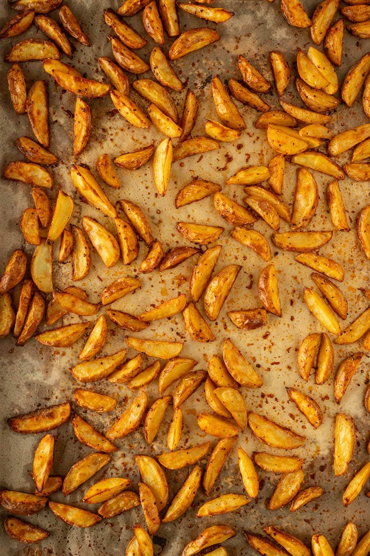 Knusprig gebackene, goldbraune Kartoffelspalten auf einem mit Backpapier ausgelegten Backblech.