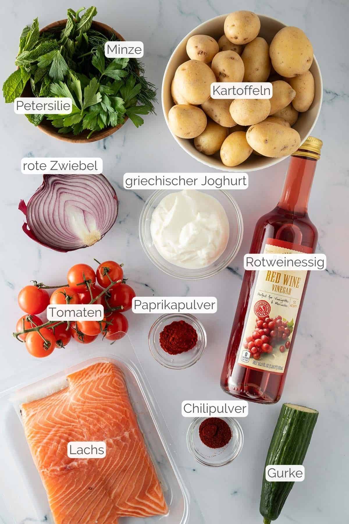 Alle Zutaten mit jeweiligen Textbeschriftungen, die für die mediterrane Lachs Bowl benötigt werden.