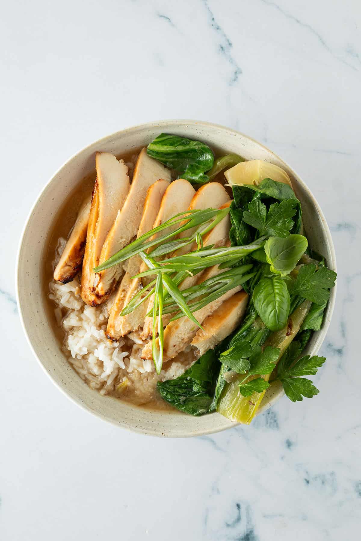 Miso Broth Bowl mit Reis, geschnittenem H&auml;hnchen, Pak Choi, Fr&uuml;hlingszwiebeln und Kr&auml;utern.
