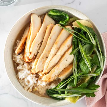 Miso Broth Bowl mit Reis, H&auml;hnchen und Pak Choi in einer hellen Sch&uuml;ssel, serviert mit Fr&uuml;hlingszwiebeln und Kr&auml;utern.