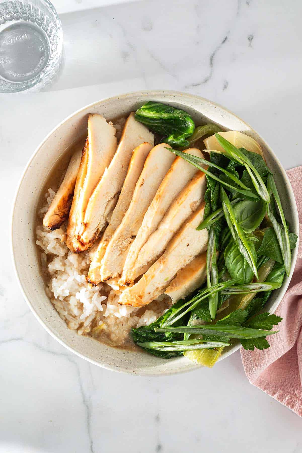 Miso Broth Bowl mit Reis, H&auml;hnchen und Pak Choi in einer hellen Sch&uuml;ssel, serviert mit Fr&uuml;hlingszwiebeln und Kr&auml;utern.