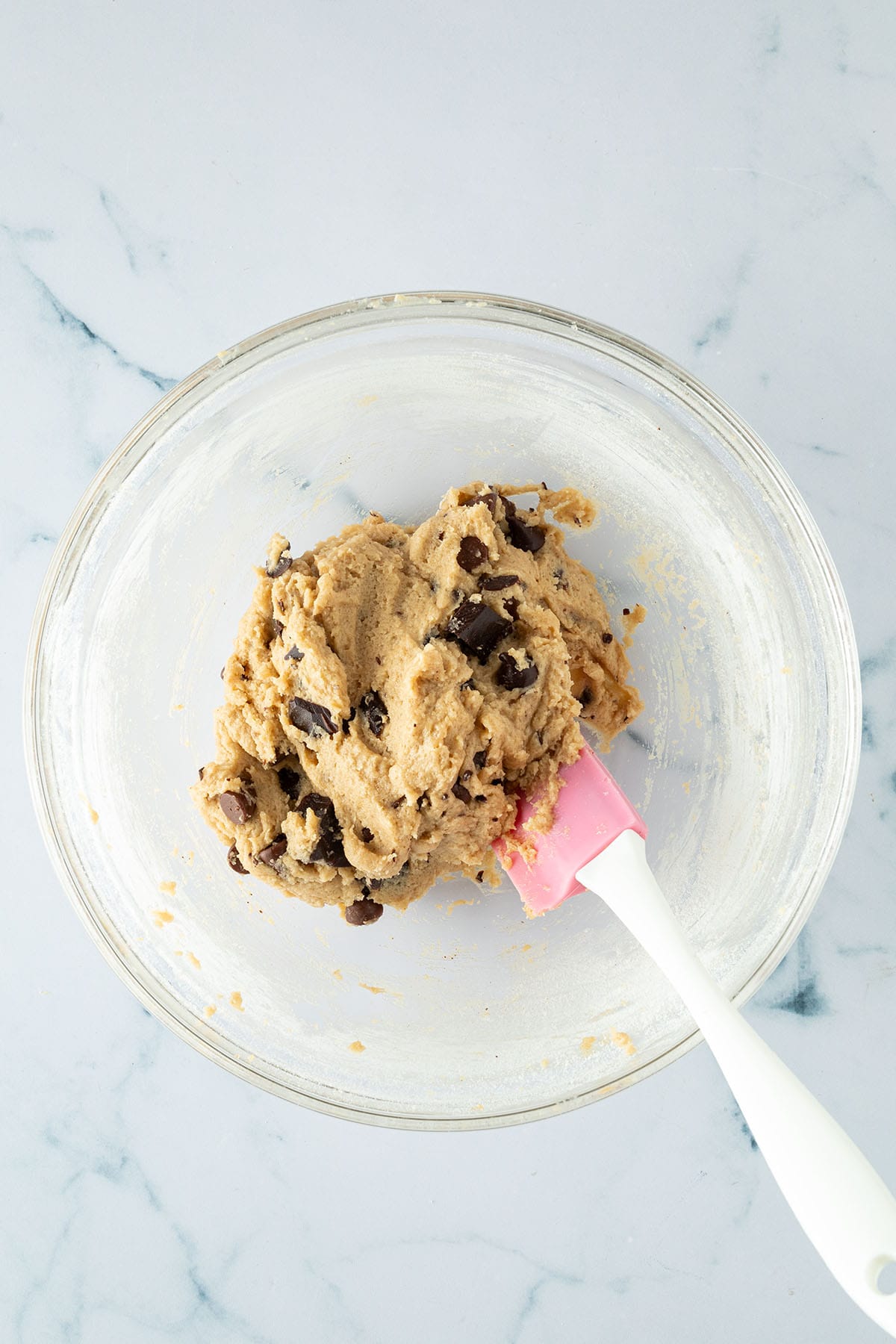 Chocolate Chip Cookie-Teig mit eingearbeiteten Schokodrops in einer Glasschüssel.