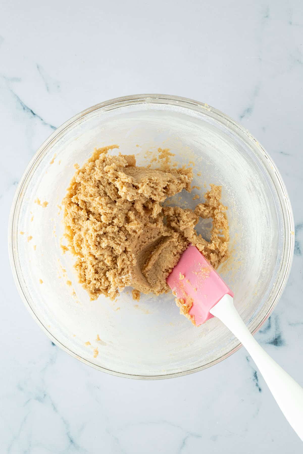 Trockene und feuchte Zutaten wurden zu einem leicht feuchten Cookieteig verknetet in eine Glasschüssel.