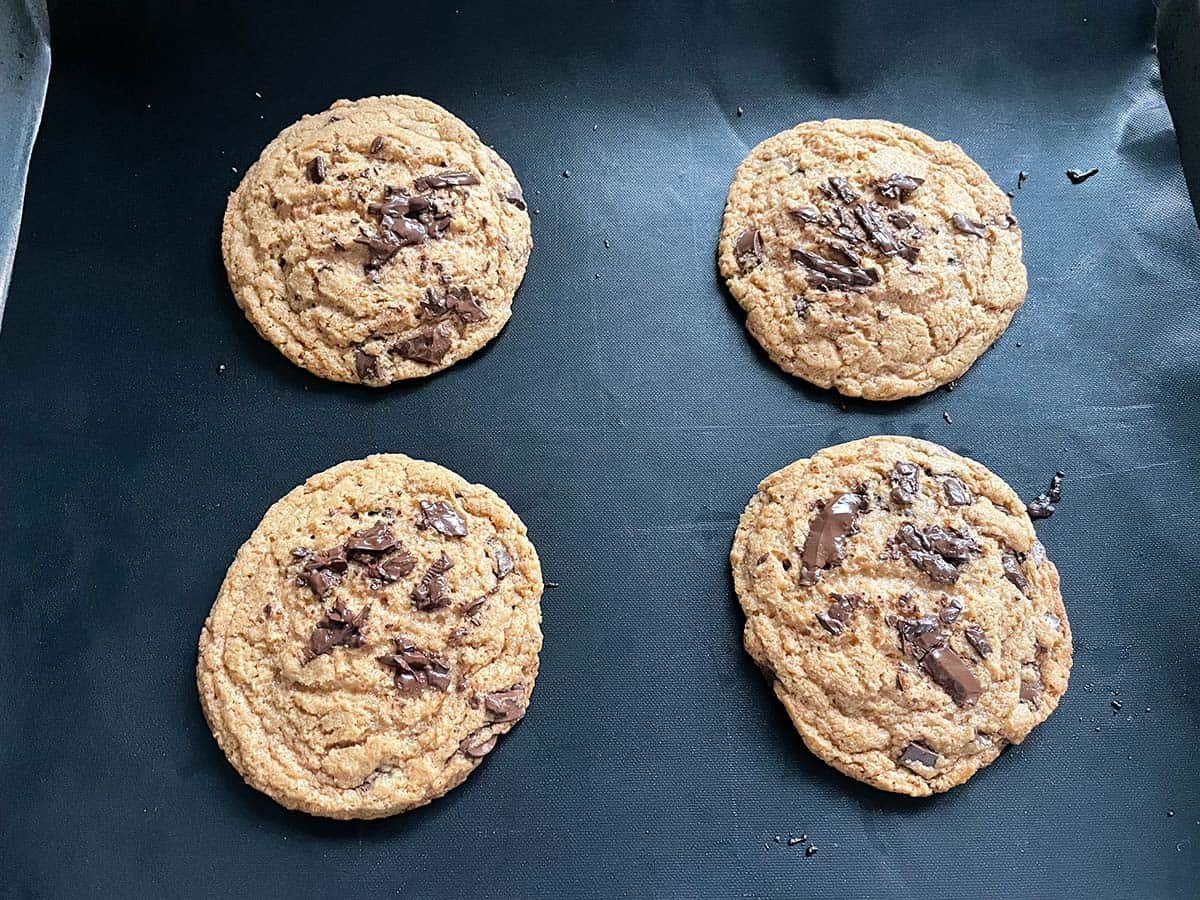 4 Chocolate Chip Cookies mit Mandelmus auf einem Blech.