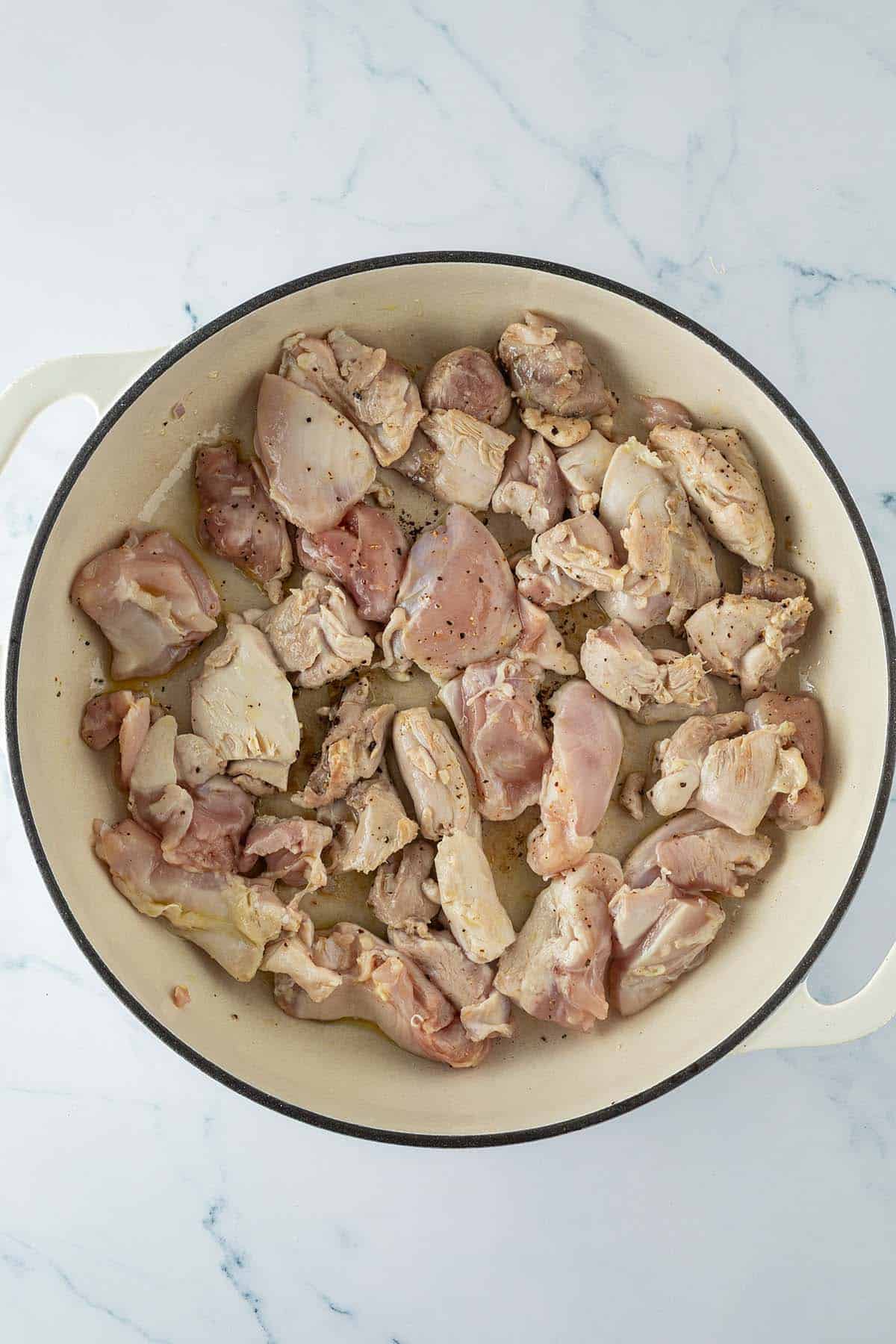 Hähnchenstücke beim Anbraten in einer großen Pfanne.
