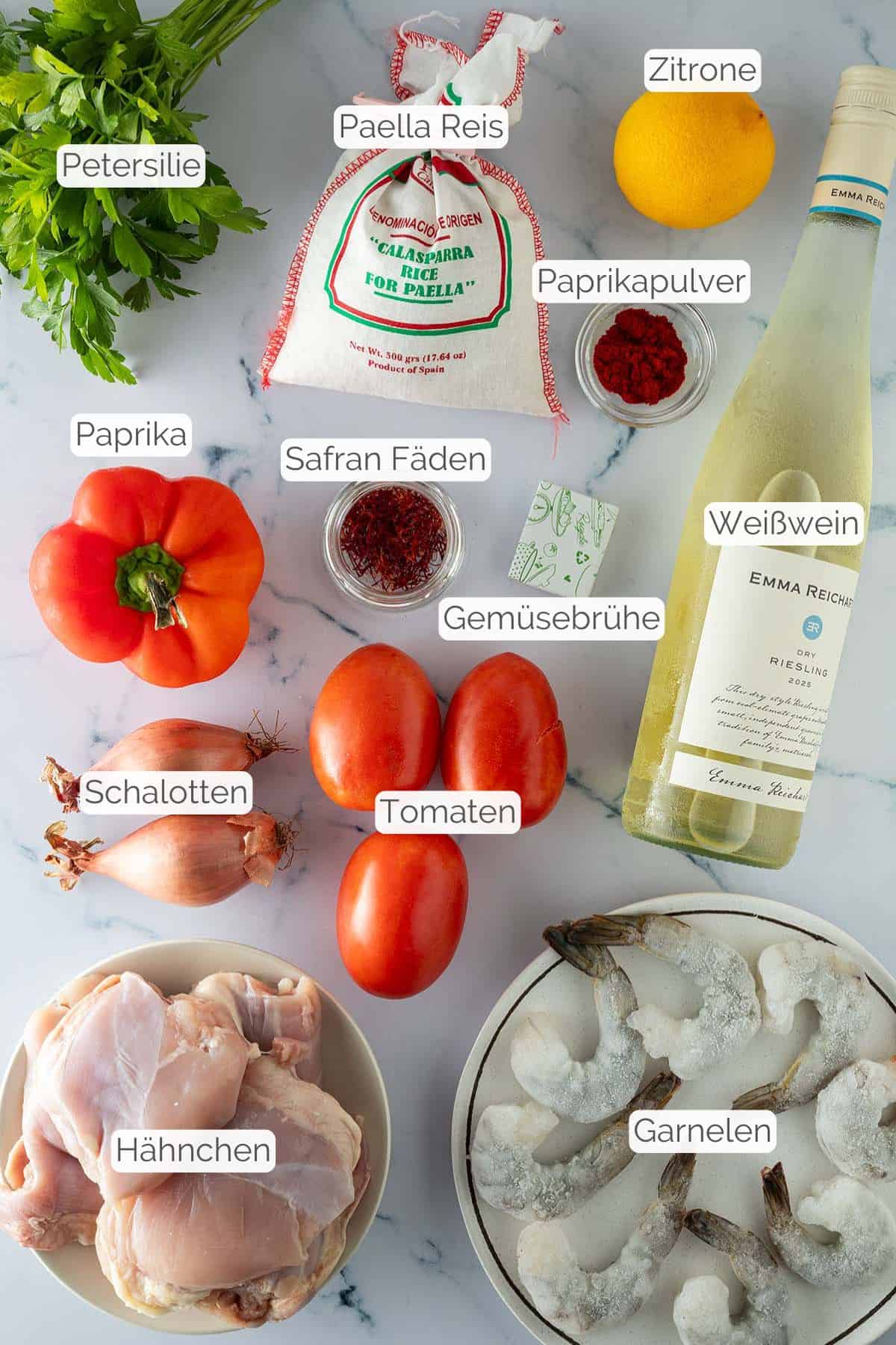 Alle Zutaten mit jeweiligen Textbeschriftungen, die für die Paella mit Hähnchen und Reis benötigt werden.